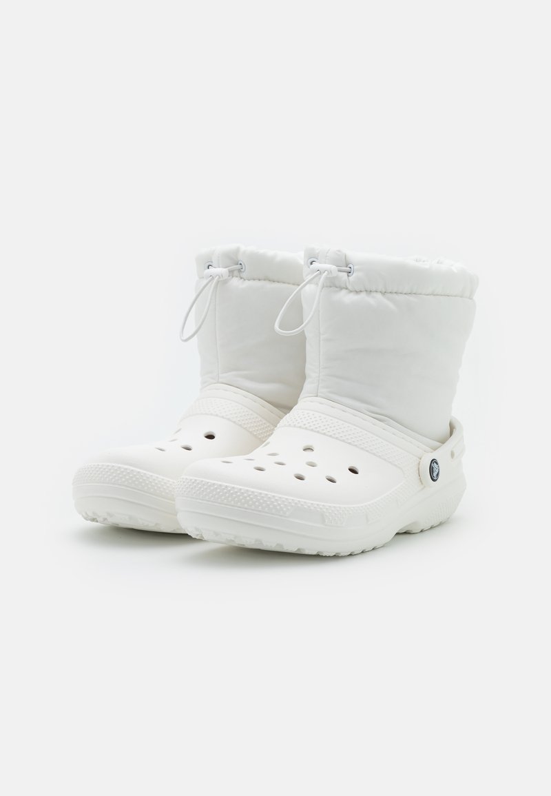 Botas de tobillo blancas aisladas con una base de plástico flexible, agujeros de ventilación y un cordón en la parte superior para un ajuste regulable.