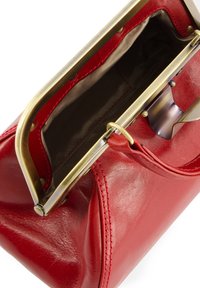 Red leather handbag with a metal clasp, featuring a smooth texture and bronze hardware. Interior has a contrasting fabric lining.