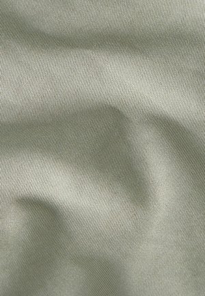 Lichtgroene stof met fijne diagonale ribbelstructuur en zachte plooien die subtiele schaduwen creëren.