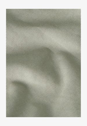 Lichtgroene stof met fijne diagonale ribbelstructuur en zachte plooien die subtiele schaduwen creëren.