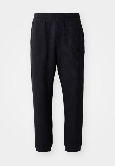 Svarte, avslappede bukser laget av teksturert stoff, med elastisk midje og smale mansjetter. Ingen synlige lommer eller dekorasjoner.