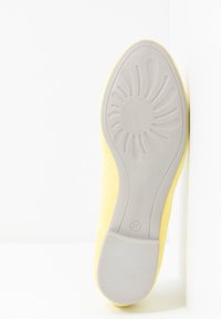 Semelle de chaussure jaune avec motif de bande de roulement en forme de fleur et numéro de taille 37 affiché en bas au centre.
