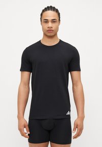 Schwarzes T-Shirt mit kurzen Ärmeln aus glattem Stoff, mit Rundhalsausschnitt und einem weißen Adidas-Logo auf der linken unteren Seite.