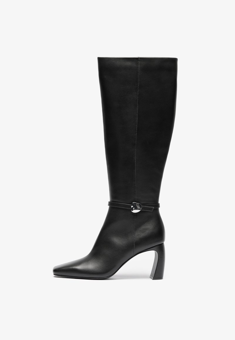 Bottes noires en cuir montantes avec un bout pointu et un talon épais. Présente une sangle avec un accent circulaire au niveau de la cheville.