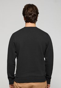 Czarna bluza z okrągłym dekoltem, długimi rękawami i ściągaczami na końcach rękawów. Miękka tekstura i minimalistyczny design, bez widocznych logo czy wzorów.
