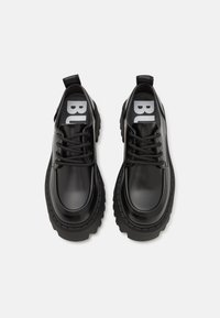 Melni ādas apavi ar masīvu zoli, apaļu purngalu, šņorēšanas dizainu un cilpu papēdī, ar izteiksmīgu zīmolu uz iekšējām zolēm.