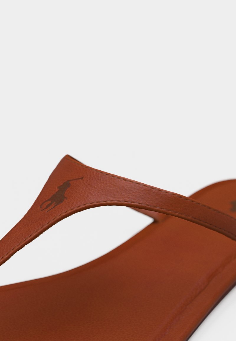 Tongs en cuir marron avec logo Polo Ralph Lauren embossé sur la bride, sur fond blanc.