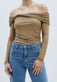 Hellbraun, schulterfreies Oberteil mit rüschendetails und langen Ärmeln, kombiniert mit hoch taillierten blauen Jeans. Glatte Textur.