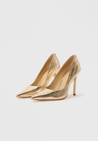 Pair of metallic gold pointed-toe high heels with stiletto heels on a plain white background.