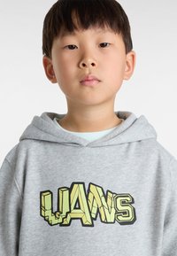 Hoodie gris avec une grande impression graphique "LANS" en jaune et noir, avec un design texturé sur un matériau doux, semblable à de la polaire.