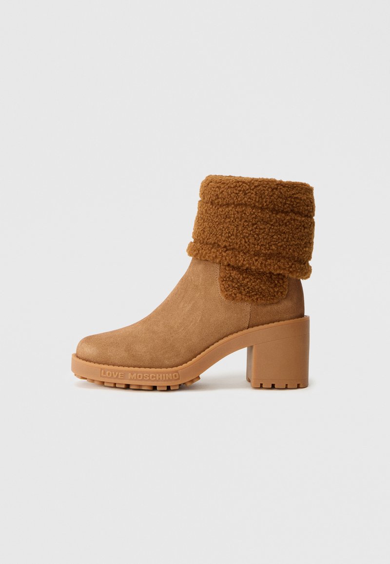 Botine maro din suede, cu toc gros, mansetă din shearling pliată și inscripția "Love Moschino" pe talpă.