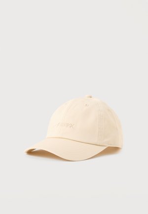 Béžová šiltovka s mierne zakriveným štítkom a vyšitým logom "ARKK" na prednej strane, zobrazená na jednoduchom svetlom pozadí.