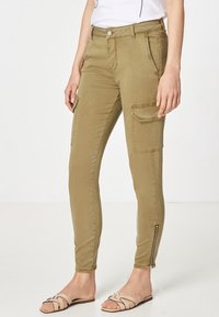 Khaki cargo-housut, joissa on kapea istuvuus, valmistettu pehmeästä puuvillasekoitteesta, varustettu vetoketjullisilla nilkoilla ja kahdella sivutaskulla käytännöllisyyttä varten.