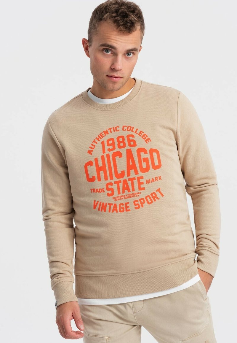 Felpa beige con texture a coste, scollo rotondo e stampa grafica arancione con la scritta "1986 CHICAGO VINTAGE SPORT". Maniche lunghe e vestibilità slim.