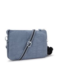 Borsa a tracolla blu in nylon con superficie texturizzata, accessori in argento, tracolla regolabile nera e grigia, e dettaglio in pompon nero.
