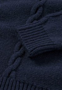 Dunkelblaues Strickpullover Nahaufnahme, mit einem strukturierten Muster, gerippten Bündchen und erhabenen Zopfmustern für zusätzliche Details. Aus weichem Wollmaterial.