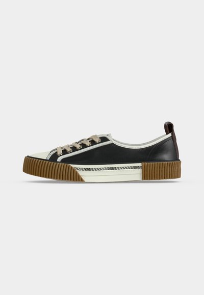 Μαύρο sneaker χαμηλού ύψους με λευκή επένδυση, μπεζ κορδόνια, σόλα από καουτσούκ χρώματος τσίχλας και γεωμετρικό σχέδιο στην πλαϊνή σόλα.