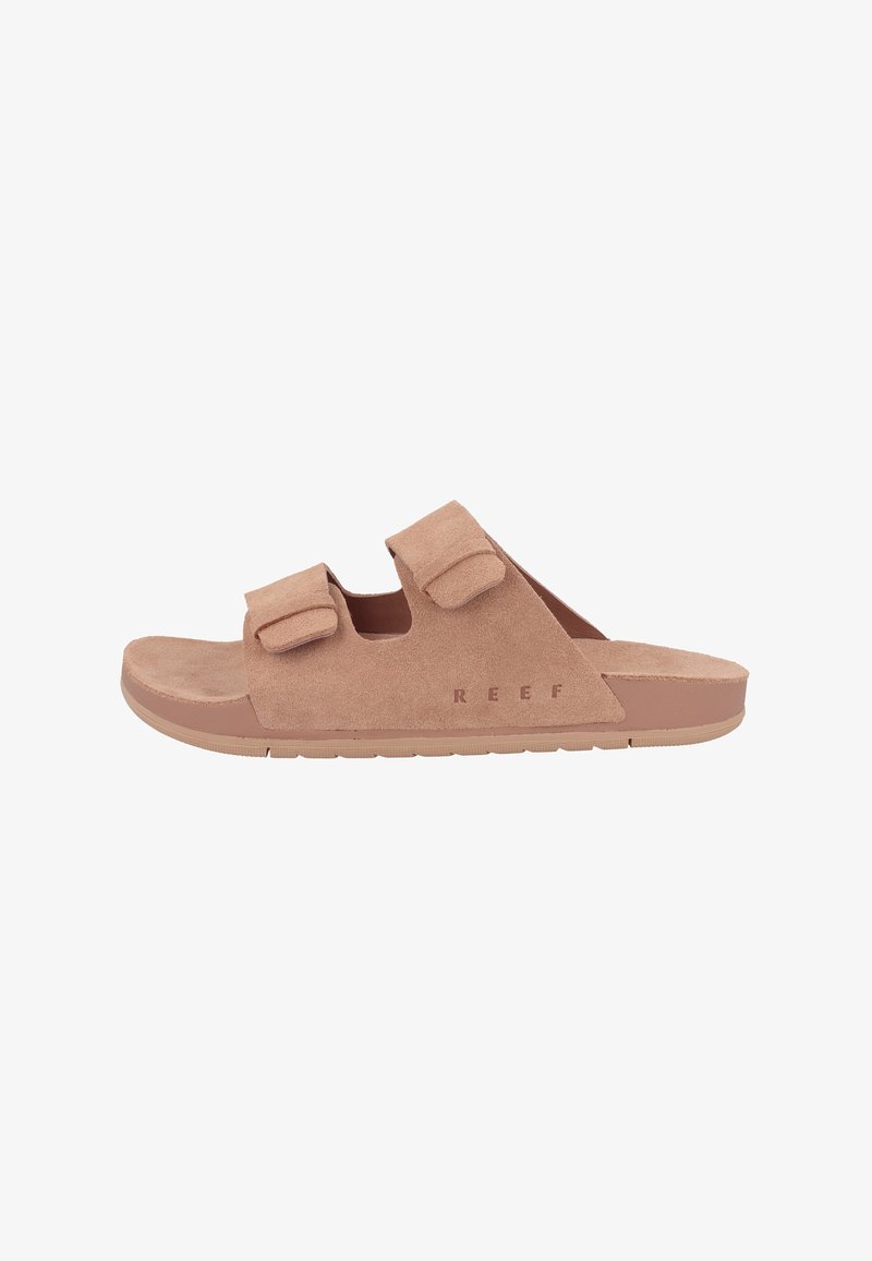 Suede slip-on sandaler i ljusbrunt med två justerbara Velcro-remmar och en texturerad gummisula. Märkesnamnet "REEF" tryckt på sidan.