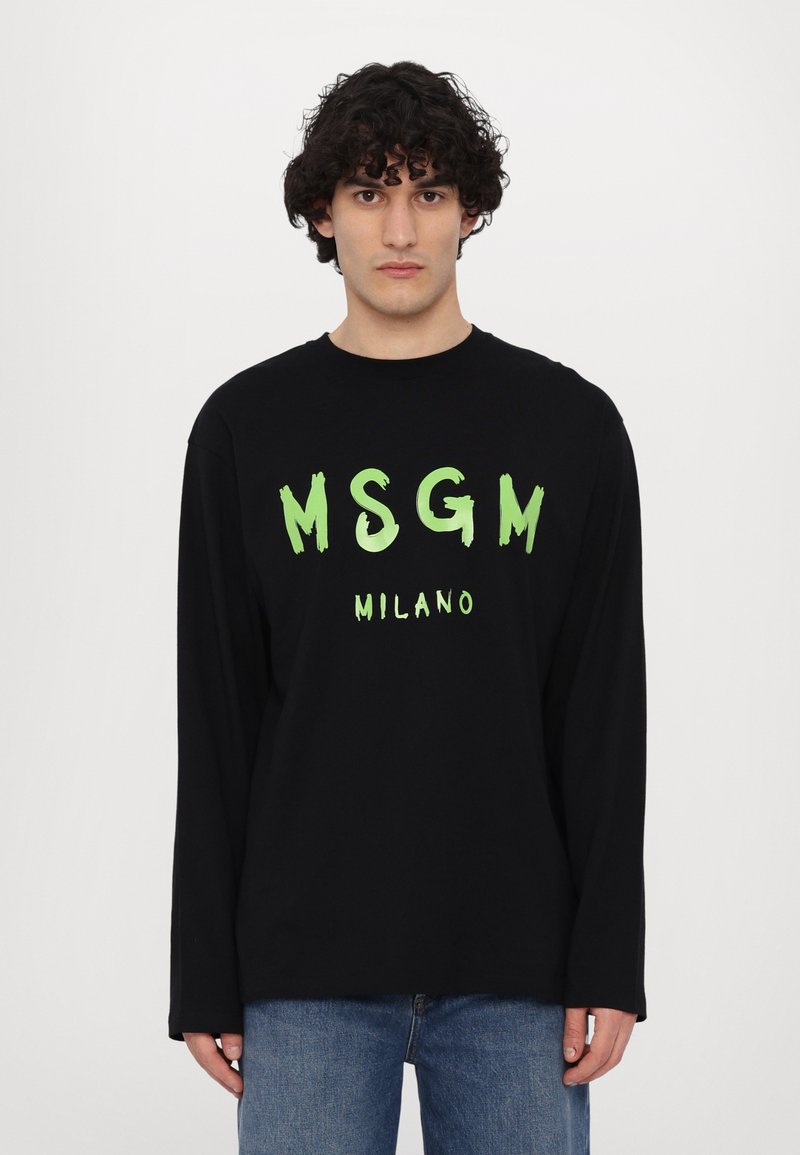 Svart langermet T-skjorte med grønn penselstrøk "MSGM MILANO" tekst. Laget av bomull, med rund hals og avslappet passform. Denim jeans brukt under.