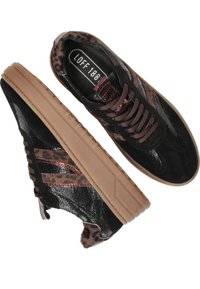 Baskets noires avec une finition en cuir texturé, des accents à motif léopard et une épaisse semelle en caoutchouc beige. Elles disposent de lacets marron et d'œillets en métal.