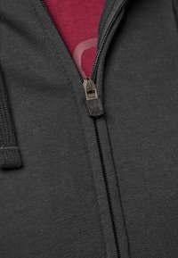 Fekete cipzáras kapucnis pulóver sima felülettel, elülső cipzár részlettel, és bordó belső pólóval, amelyen diszkrét grafikai mintázat található.