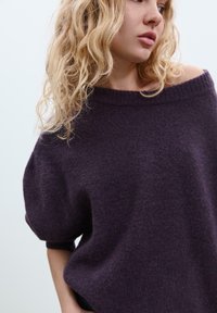 Lila übergroßer Pullover mit weitem Ausschnitt und kurzen, puffähnlichen Ärmeln. Weiche Textur, mit gerippten Bündchen und Saum.