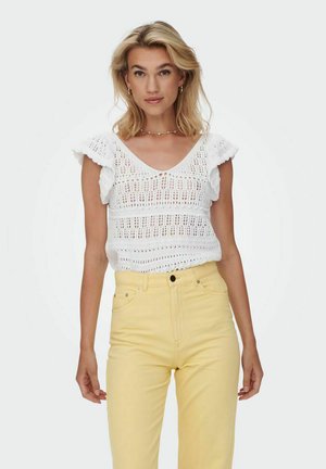 Top bianco lavorato a maglia con maniche corte e svasate, caratterizzato da un motivo ad uncinetto aperto. Abbinato a jeans gialli a vita alta.