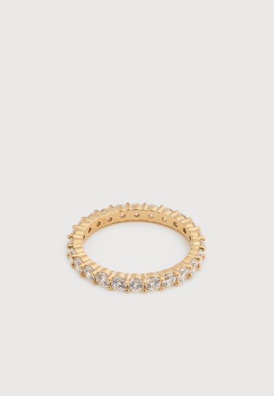 Bague éternelle en or sertie de pierres précieuses rondes et transparentes tout autour de l'anneau sur un fond blanc uni.