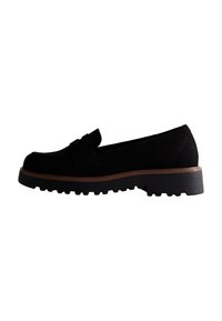Black suede loafer with a rounded toe, decorative bow detail, and a thick rubber sole featuring a ridged pattern for traction.