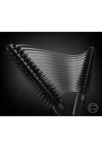 Deux brosses à mascara noires avec des poils en pointe, reliées par des traits lisses de mascara noir sur un fond sombre.