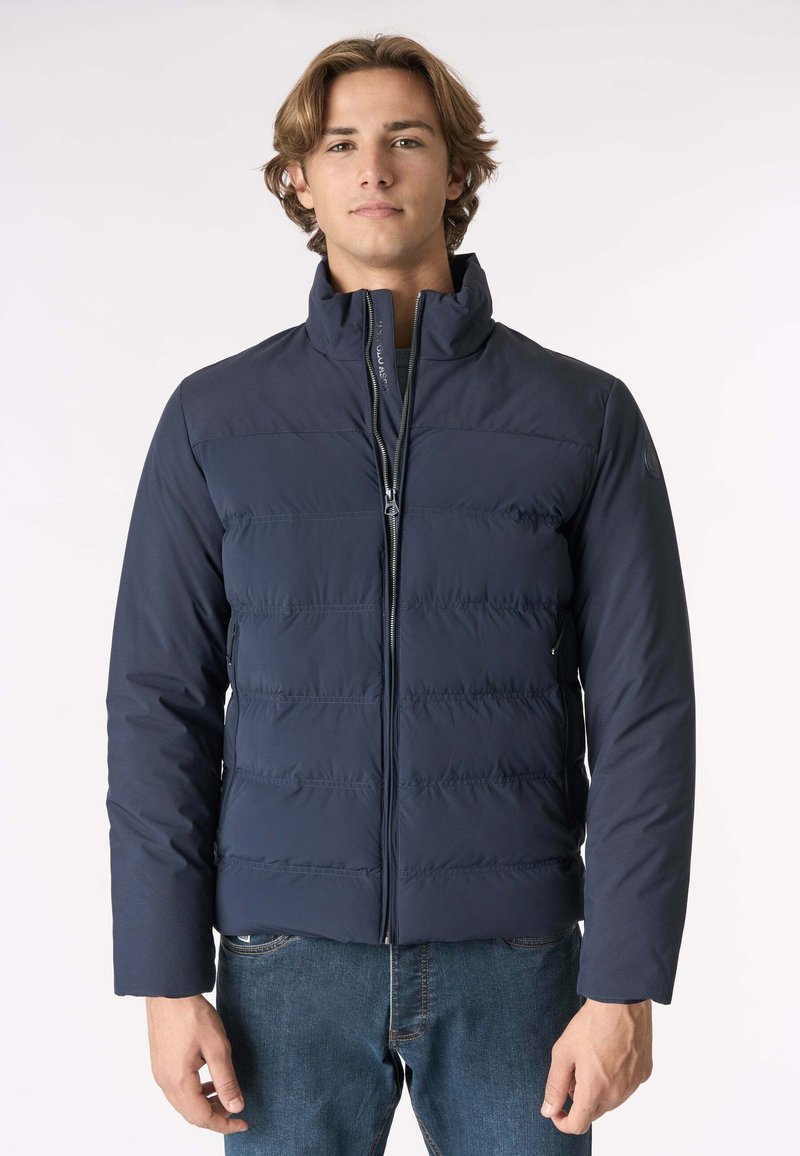 Giacca puffer blu navy con cuciture orizzontali, colletto alto e chiusura a zip; presenta una texture liscia e un design minimalista.