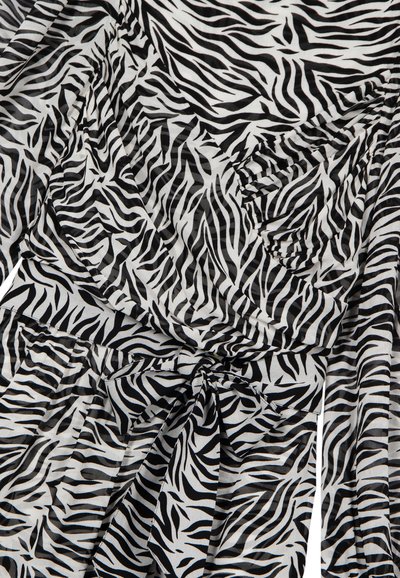 Tela en blanco y negro con rayas de cebra, textura visible y detalle de nudo envuelto, creando pliegues y sombras.
