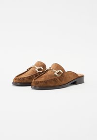 Brown suede mules with a pointed toe, decorative gold-tone chain detailing, and a low wooden heel. Stitched accent around the edge.