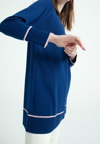 Maglione blu navy con polsini a costine, con accenti rosa sui polsi e sull'orlo. Materiale in maglia morbido, vestibilità comoda e maniche lunghe.
