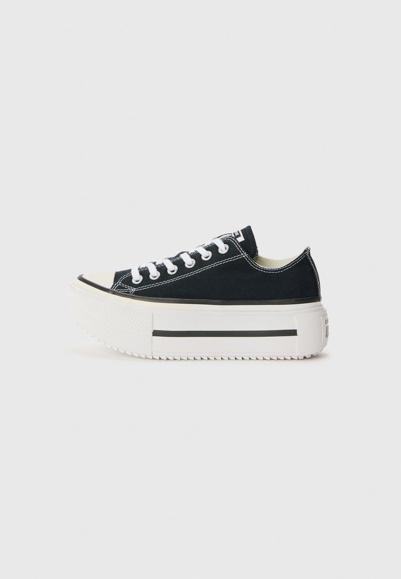 Black canvas sneakers with a white rubber sole, featuring a thick platform, white laces, and contrasting stitching along the seams.