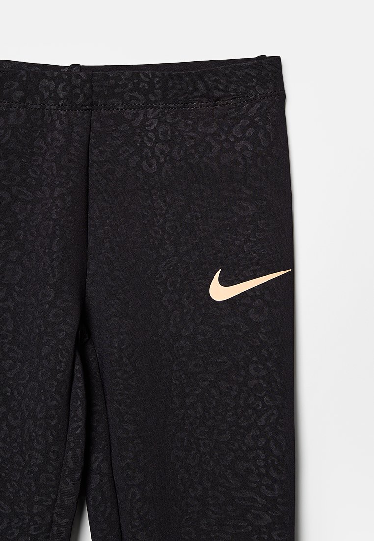 Leggings negros con un sutil estampado de leopardo, que presentan un logo de swoosh dorado de Nike en el lado inferior. Tela suave con una cintura elástica.