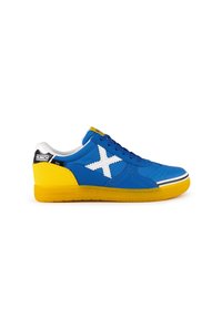 Zapatilla azul y amarilla con parte superior de lona, costuras blancas y un gran emblema blanco en forma de X. Presenta una suela amarilla texturizada y un logo negro.
