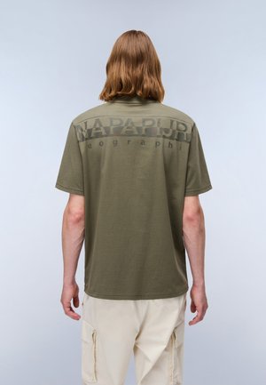 Olive green cotton t-shirt with short sleeves, featuring a large logo in black on the back. The design is simple with a relaxed fit.