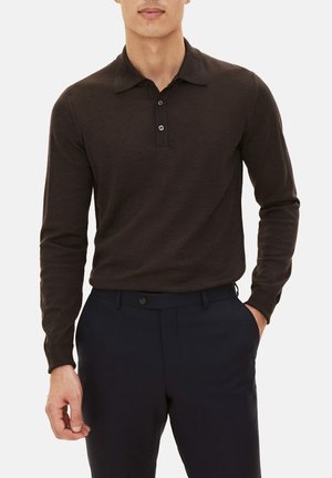 Langärmliges, dunkelbraunes Polohemd mit strukturiertem Kragen, Dreiknopf-Leiste und weicher Textur, kombiniert mit dunkelblauen Anzughosen.