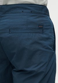 Μπλε παντελόνι από ύφασμα με υφή, διαθέτει πίσω τσέπη και μια μικρή ραμμένη ετικέτα με λογότυπο. Απλός σχεδιασμός με άνετη εφαρμογή.