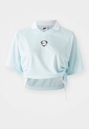 Camisa polo recortada de color azul claro hecha de tela texturizada, con un logo de Nike negro, cuello blanco y lazos ajustables en los laterales.