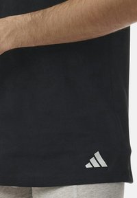 Svart bomulls t-shirt med korta ärmar, med en vit tre-randig logotyp vid fållen, slät textur och regular fit.