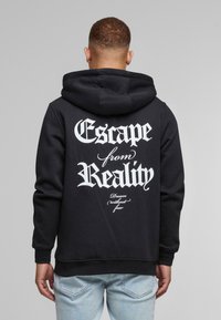 Sort hættepullover med en rummelig hætte, der har hvid tekst "Escape from Reality" og "Dream (without fear)" i stiliseret font på ryggen.
