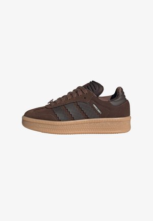 Baskets en suede marron avec une bande latérale texturée de couleur marron foncé et une semelle en caoutchouc marron clair. Comprend un col rembourré et des lacets plats.