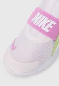 Sneaker rosa e bianca con tomaia in rete, dotata di una fascia rosa con il logo "NIKE" e accenti verdi sui lati. Texture liscia.