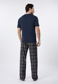 Vyriškas tamsiai mėlynas trumpomis rankovėmis viršus derinamas su languotomis flanelinėmis kelnėmis mėlynos, rudos ir baltos spalvų. Minkštas audinys, laisvas siluetas ir tiesios kojų formos dizainas.