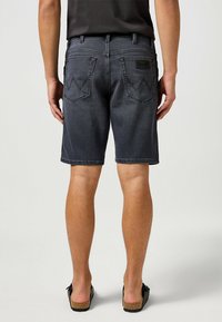 Pantaloncini cargo in denim grigio scuro, con due tasche posteriori con cuciture a zigzag, un'etichetta in pelle del marchio e una linea dritta per una vestibilità rilassata.