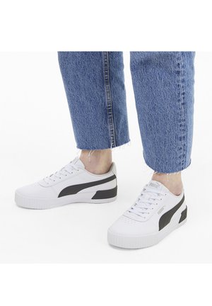 Zapatillas blancas con detalles en negro, con un diseño bajo, punta redonda y suela de goma texturizada. Los cordones son visibles y tienen detalles perforados.