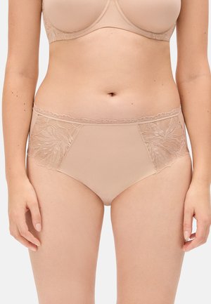 Mujer vistiendo bragas de talle alto beige con paneles de encaje floral y un sujetador a juego, de pie con los brazos relajados a los lados.