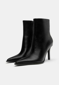 Stivali neri alla caviglia in pelle liscia, con punta affusolata, alto tacco a stiletto e zip laterale per una facile calzata.